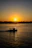 A serene sunset view from a boat gliding gently over calm waters near the coast.