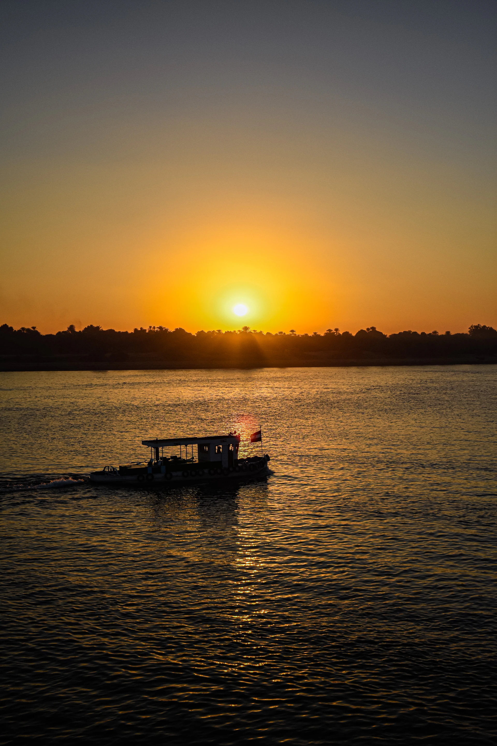 Golden sunset over the delta, with the silhouette of a boat gently gliding on the reflective water.