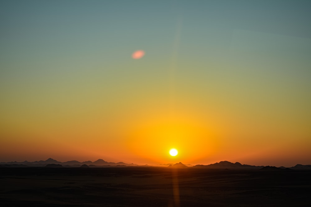 the sun is setting over the mountains in the desert