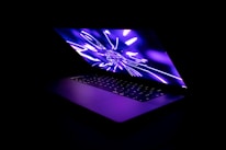 Close-up of a person watching educational videos on a sleek laptop with neon purple glow.