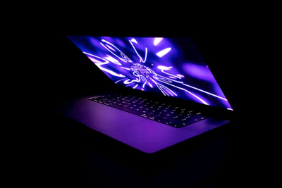 Close-up of a sleek laptop screen displaying a modern, dark-themed website with vibrant neon highlights.