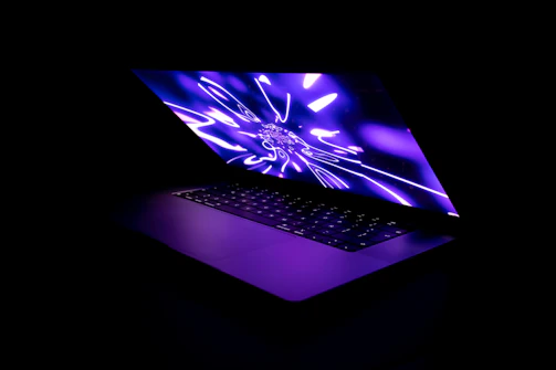 A sleek laptop displaying a vibrant, modern business website with dark blue and neon accents.