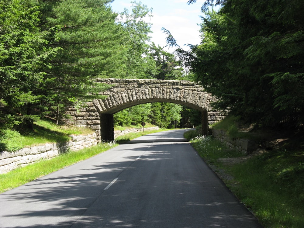 a stone bridge over a road surrounded by trees