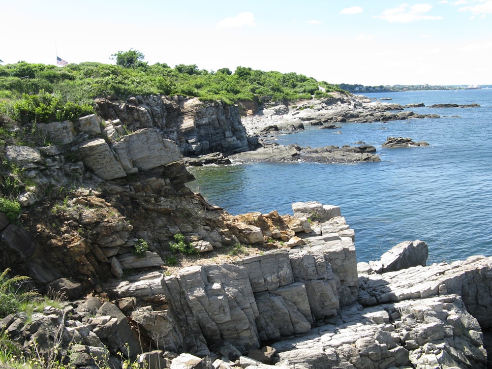 a rocky cliff with a body of water in the background