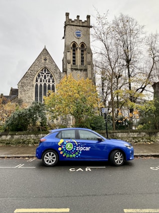 a blue car parked in front of a church