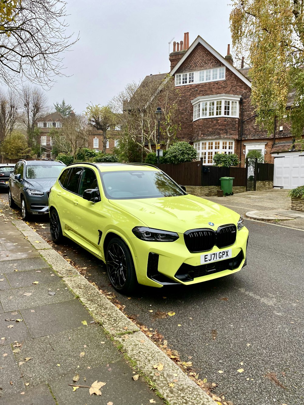 a yellow bmw suv parked on the side of the road
