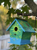 A vibrant wooden birdhouse painted in bright colors perched on a garden fence.
