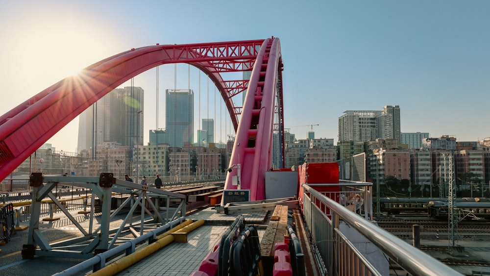 a red bridge going over a river with tall buildings in the background