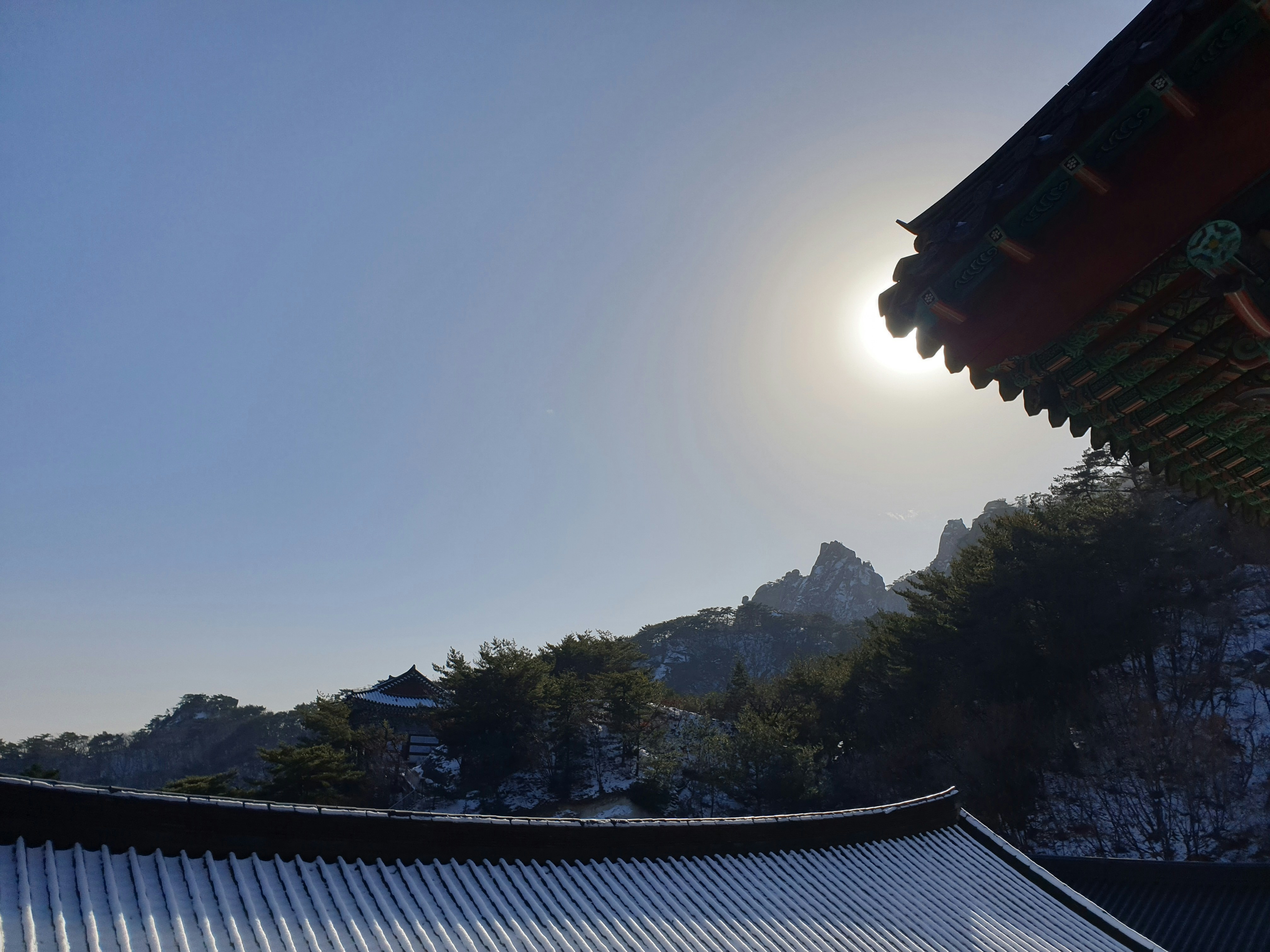 the sun is shining over a building in the mountains