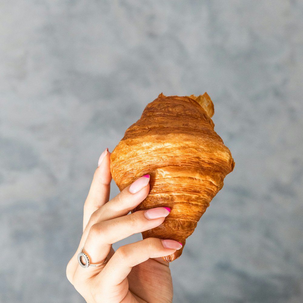 a woman holding a croissant in her hand