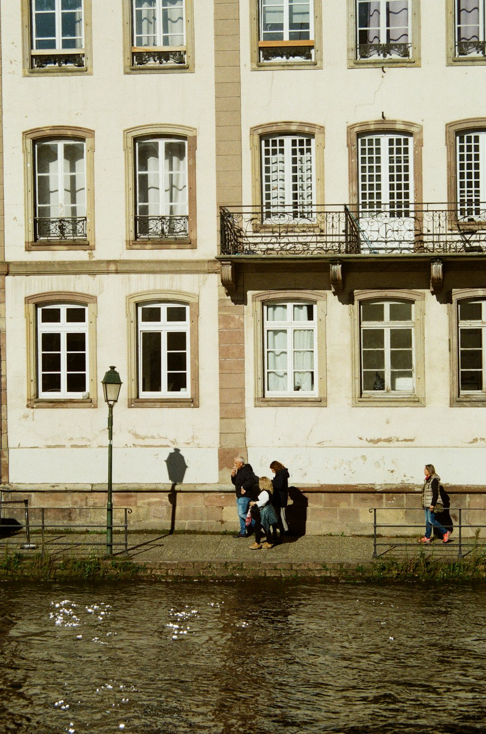 a group of people walking down a street next to a body of water