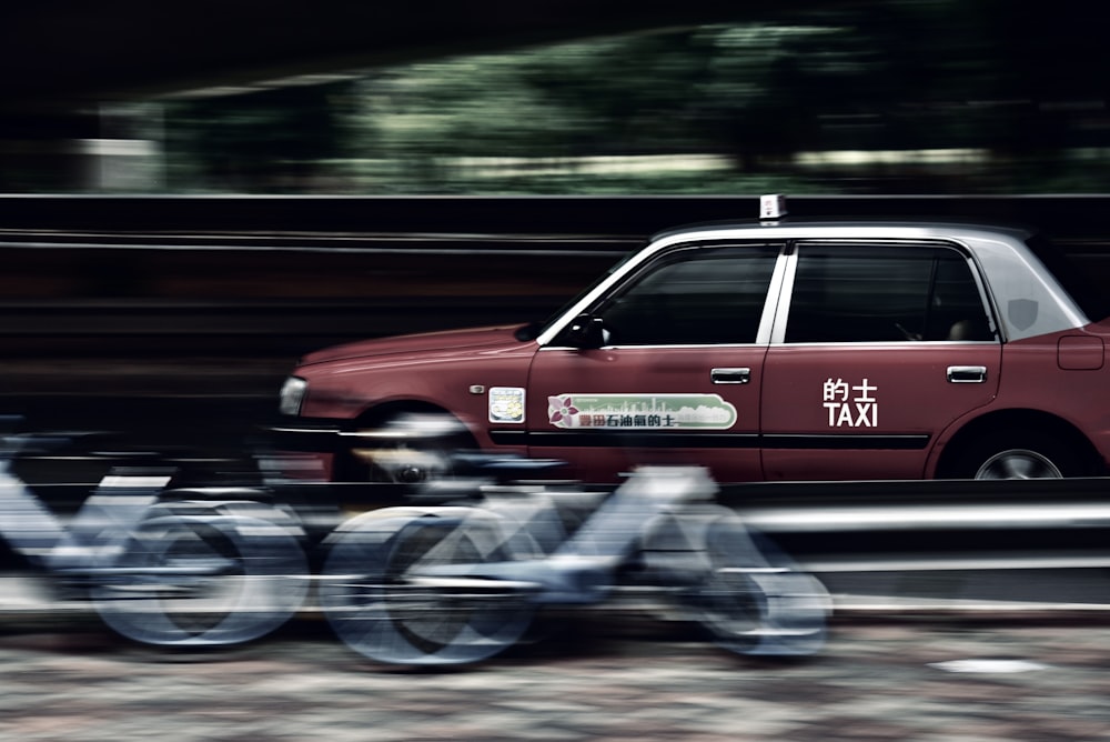 a red taxi cab driving down a street next to a bike