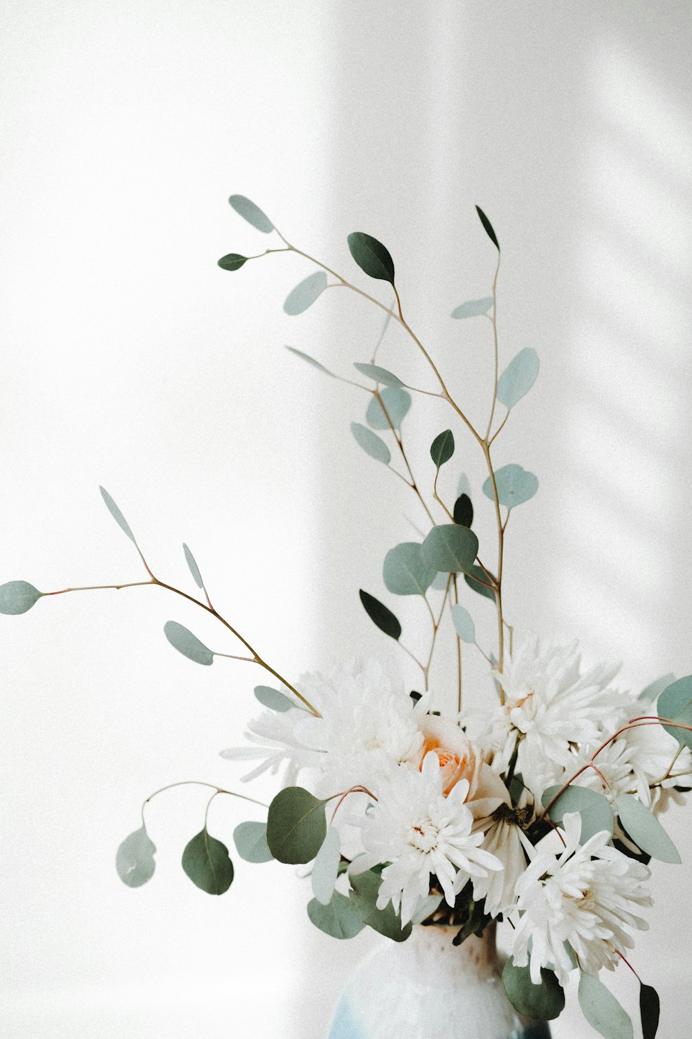 a vase filled with white flowers and greenery