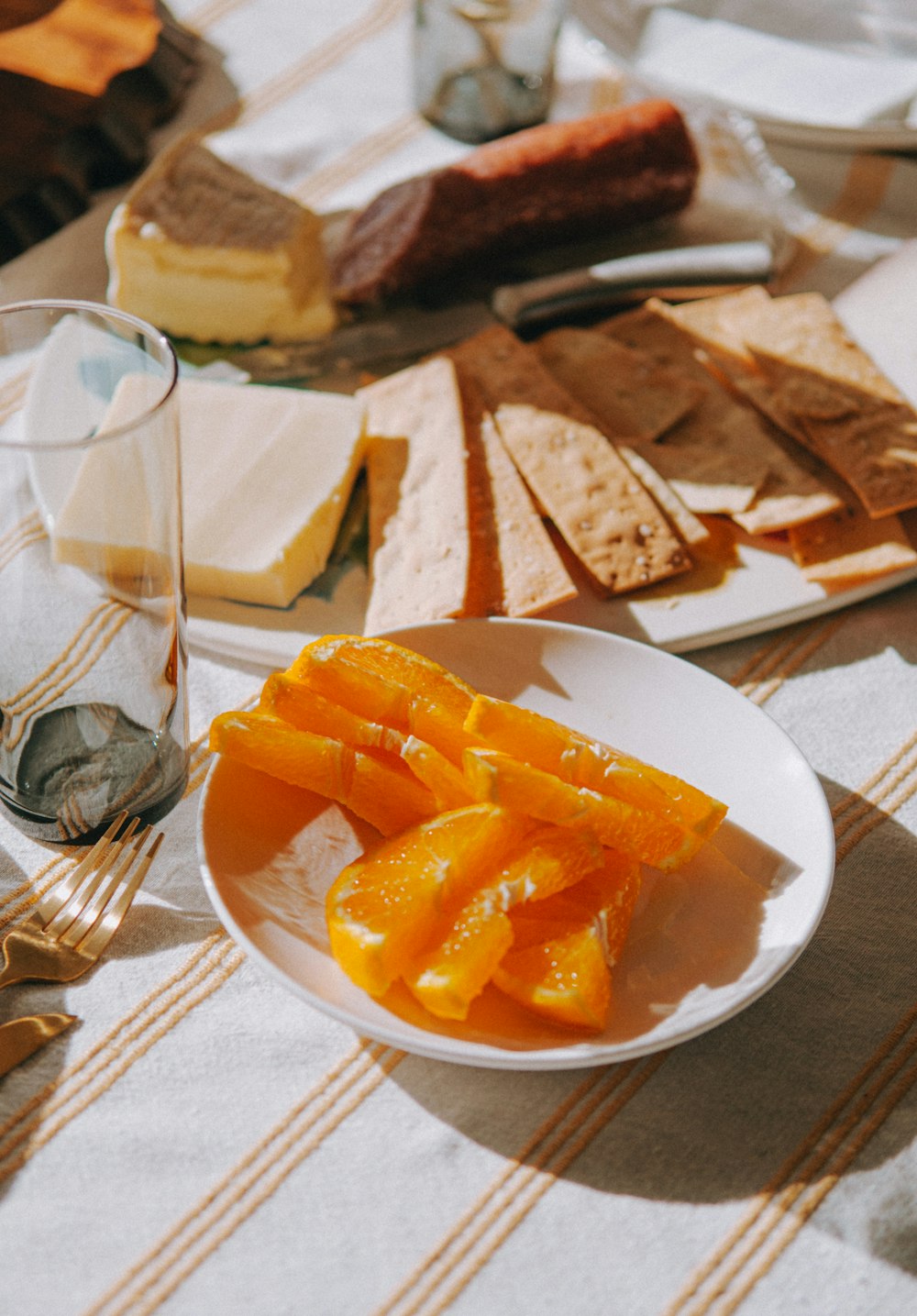 a white plate topped with sliced oranges next to a glass of wine