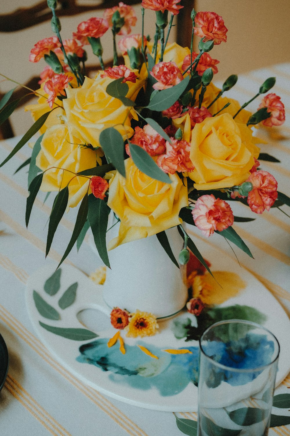 a white vase filled with yellow flowers on top of a table