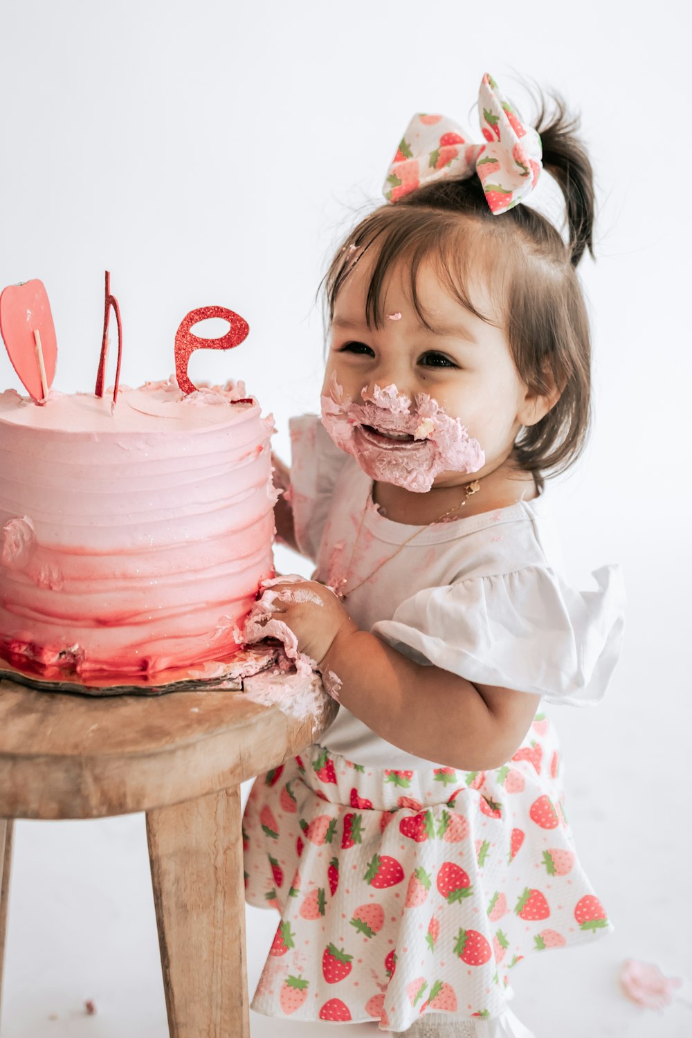 a little girl that is standing in front of a cake