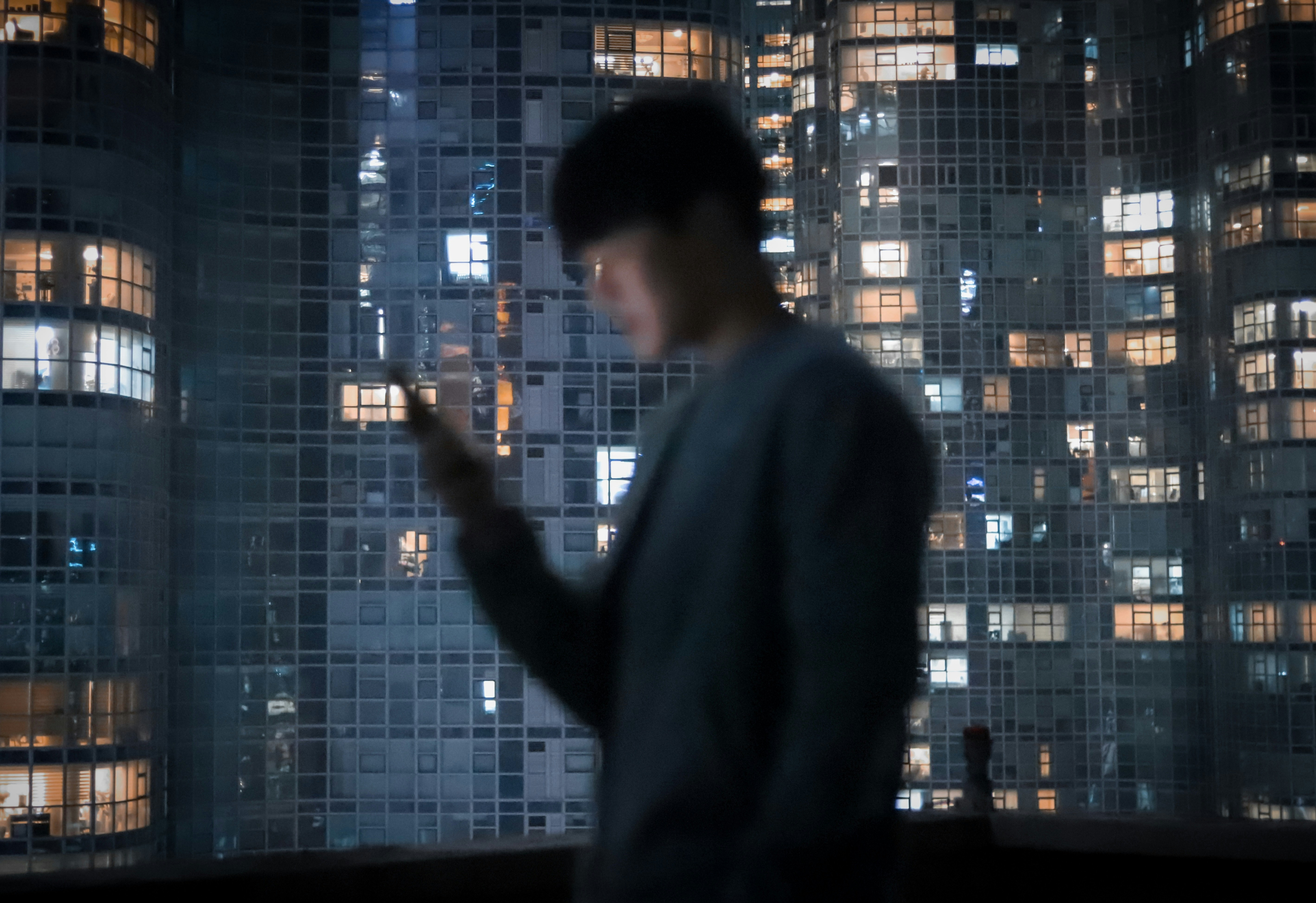 a man standing in front of a window looking at his cell phone