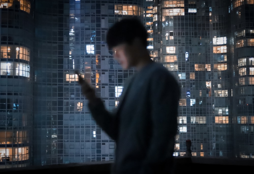 a man standing in front of a window looking at his cell phone