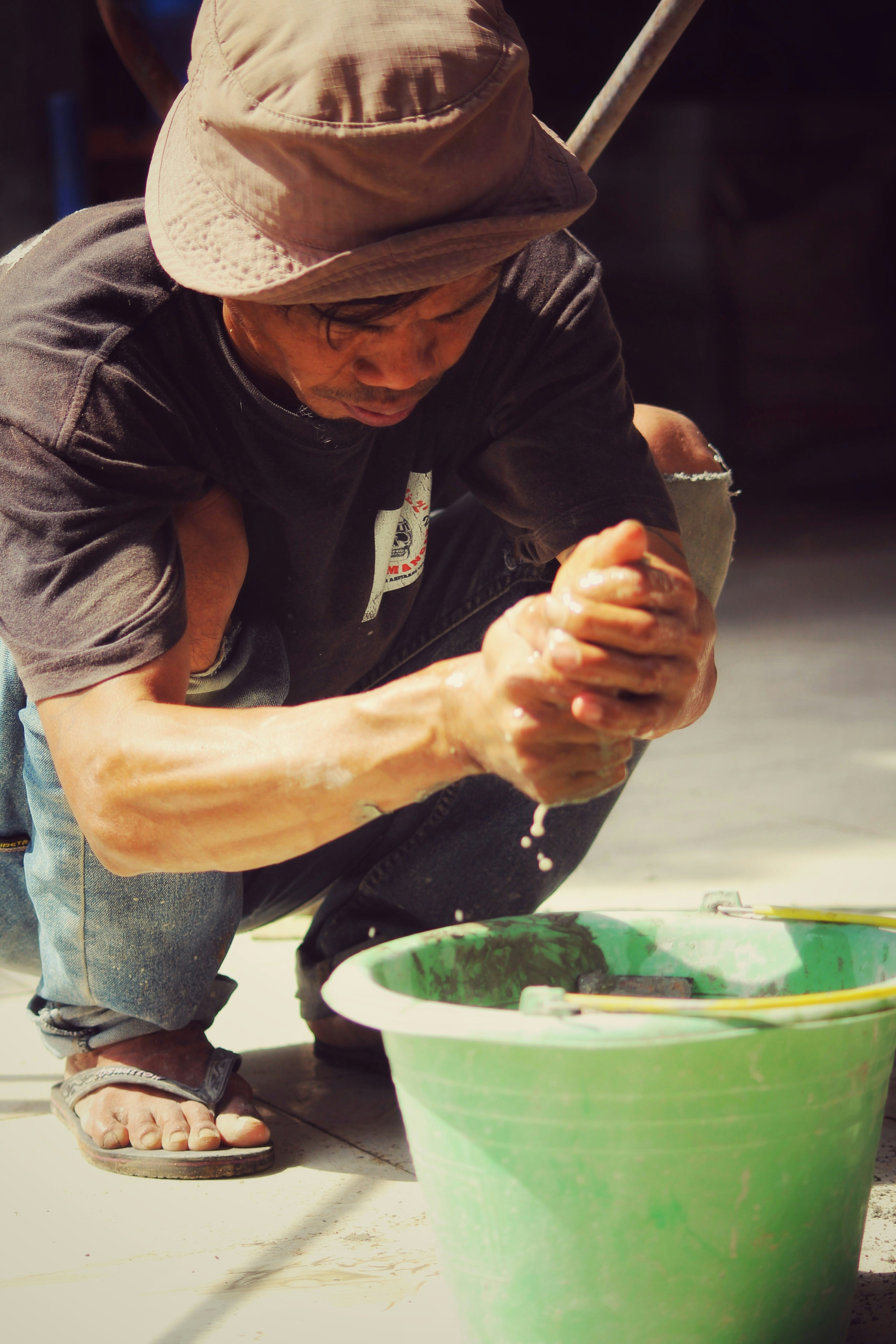 Un hombre arrodillado junto a un cubo verde