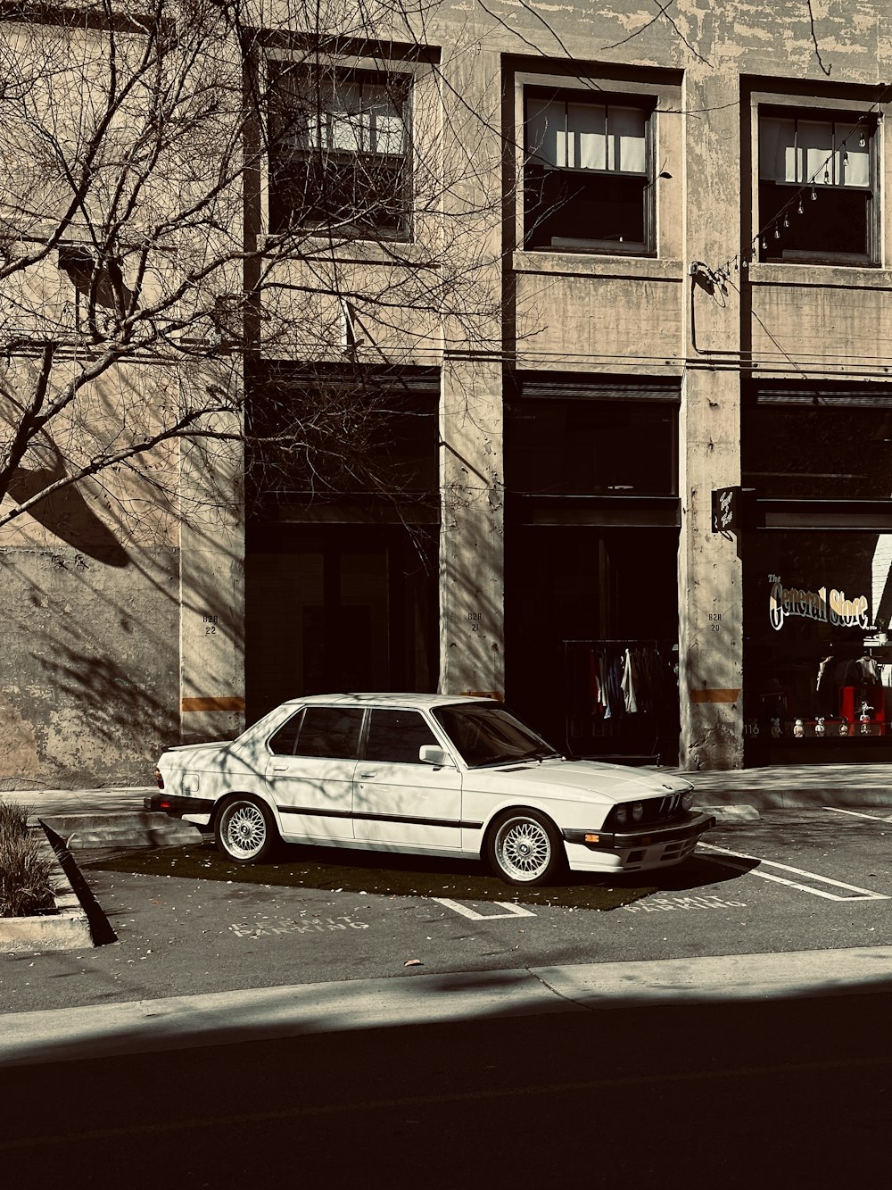 a white car parked in front of a tall building