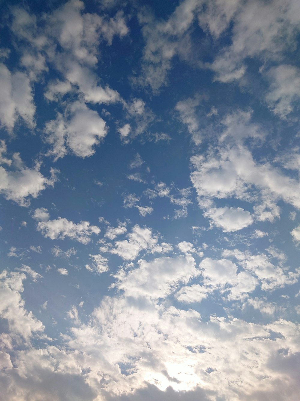 a plane flying through a cloudy blue sky