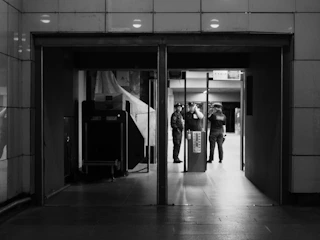 Grayscale image of a security checkpoint with an officer checking credentials.