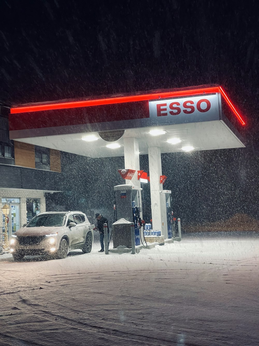 a couple of cars parked at a gas station in the snow