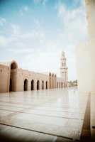 A serene courtyard with palm trees and golden light reflecting on the mosque walls
