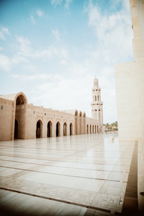 A welcoming pesantren courtyard with students engaging in study and prayer under clear blue skies.
