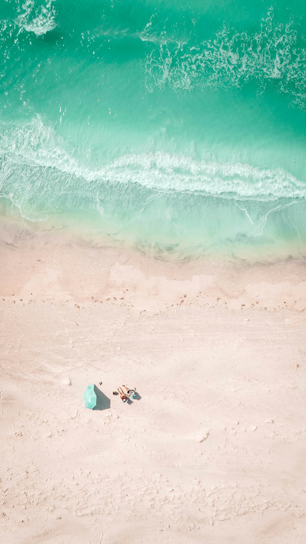 a couple of people laying on top of a sandy beach