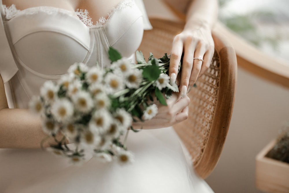a woman in a wedding dress holding a bouquet of daisies