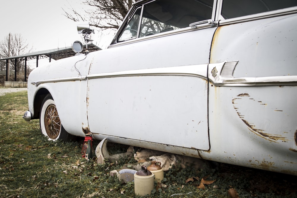 an old white car parked in a grassy field