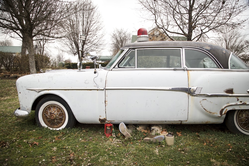 an old white car parked in the grass