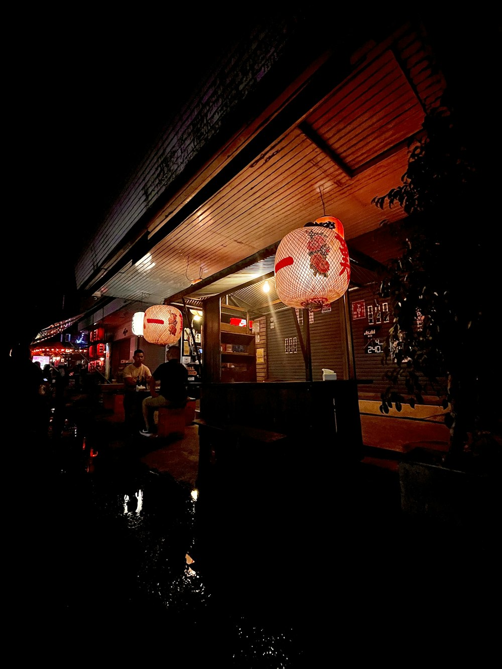 a restaurant at night with lanterns hanging from the roof