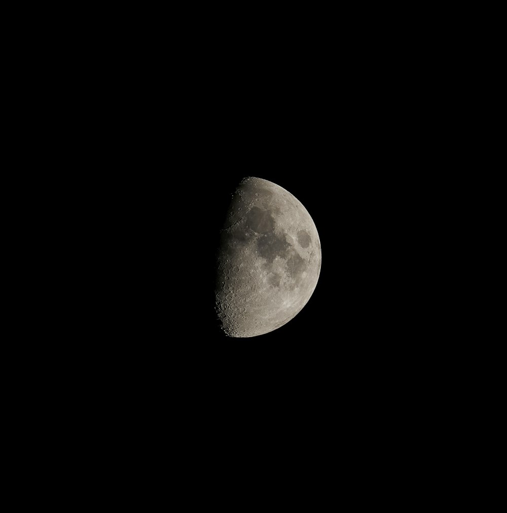 a half moon is seen in the dark sky