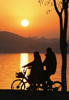 A colorful sunset over a lake with cyclists silhouetted.