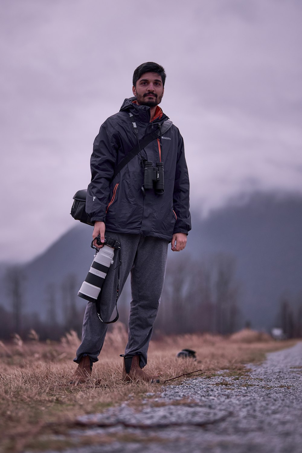 a man standing in a field holding a camera