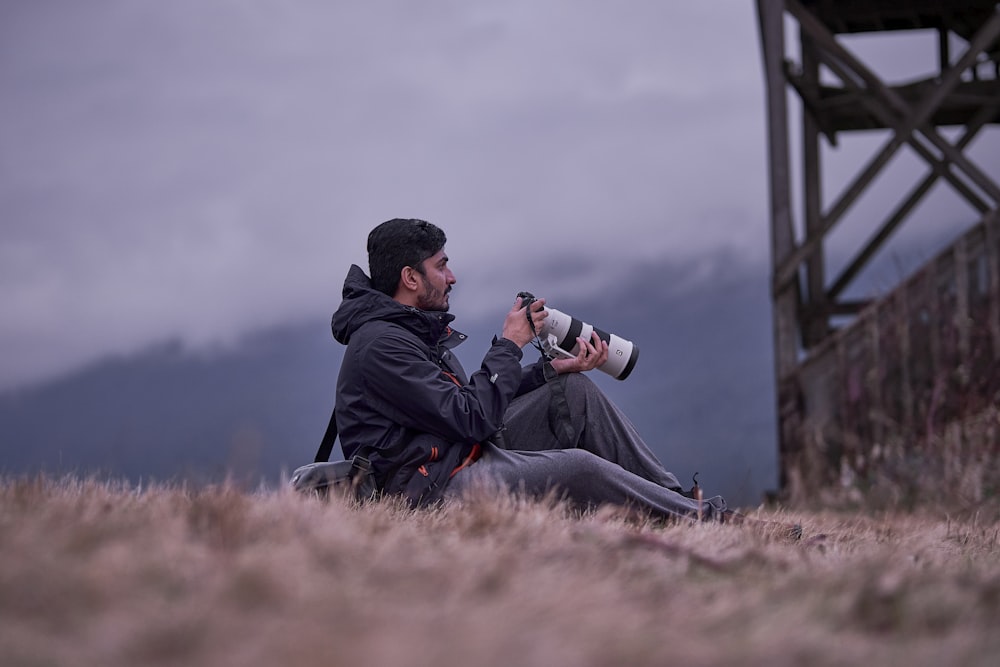a man and a woman sitting on the ground looking through binoculars