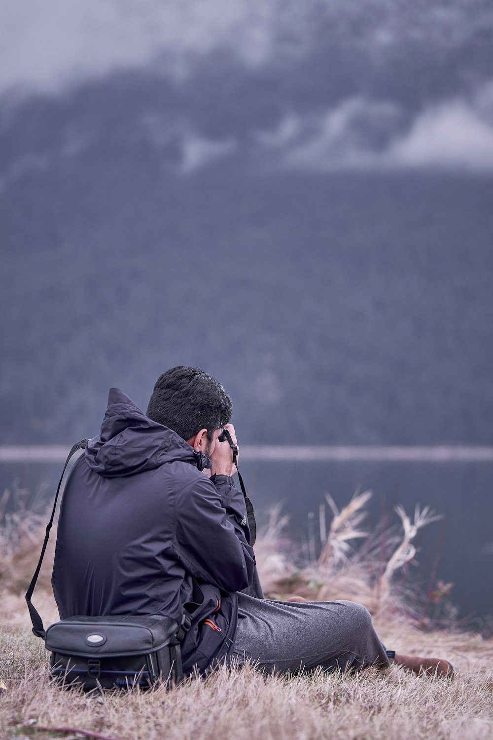 a man sitting in a field with a backpack on his back