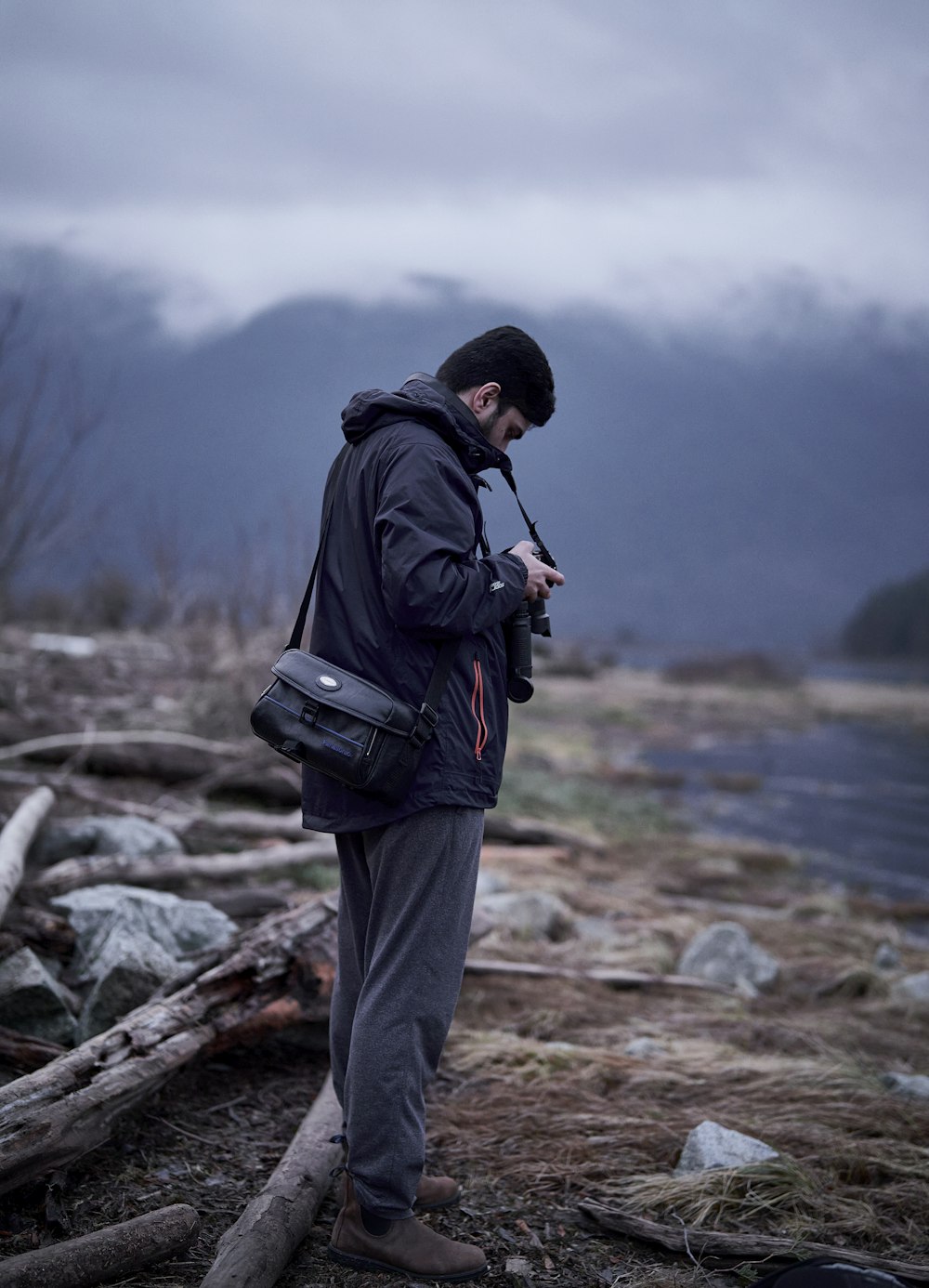 a man standing on a rocky shore looking at his cell phone