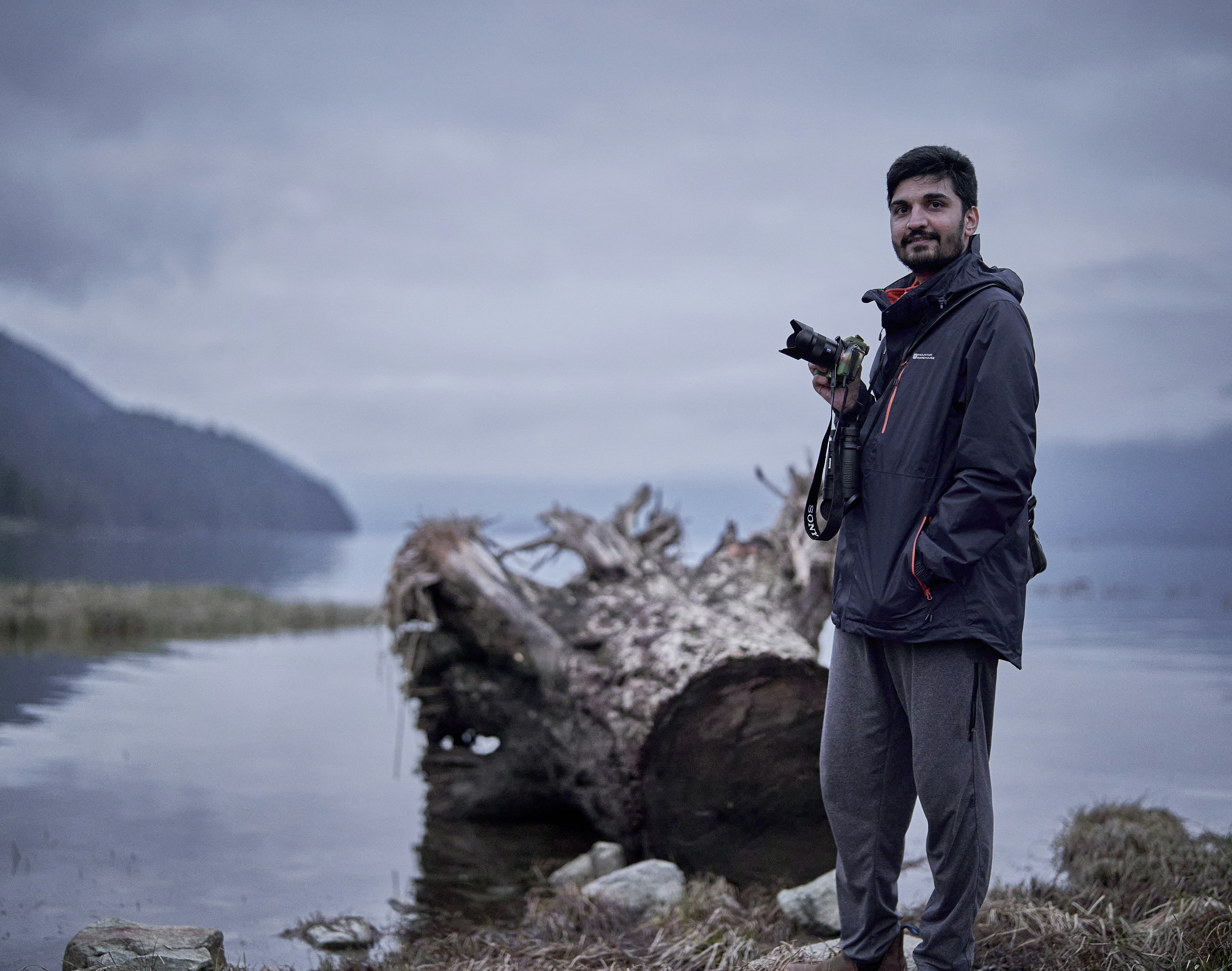Man posing with a Sony Alpha camera in front on Pitt Lake