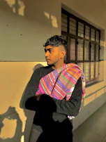 Sunlight casting shadows on a blacksess hoodie hanging against a textured wall, evoking resilience and depth.