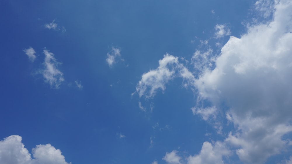 a blue sky with white clouds and a plane flying in the sky