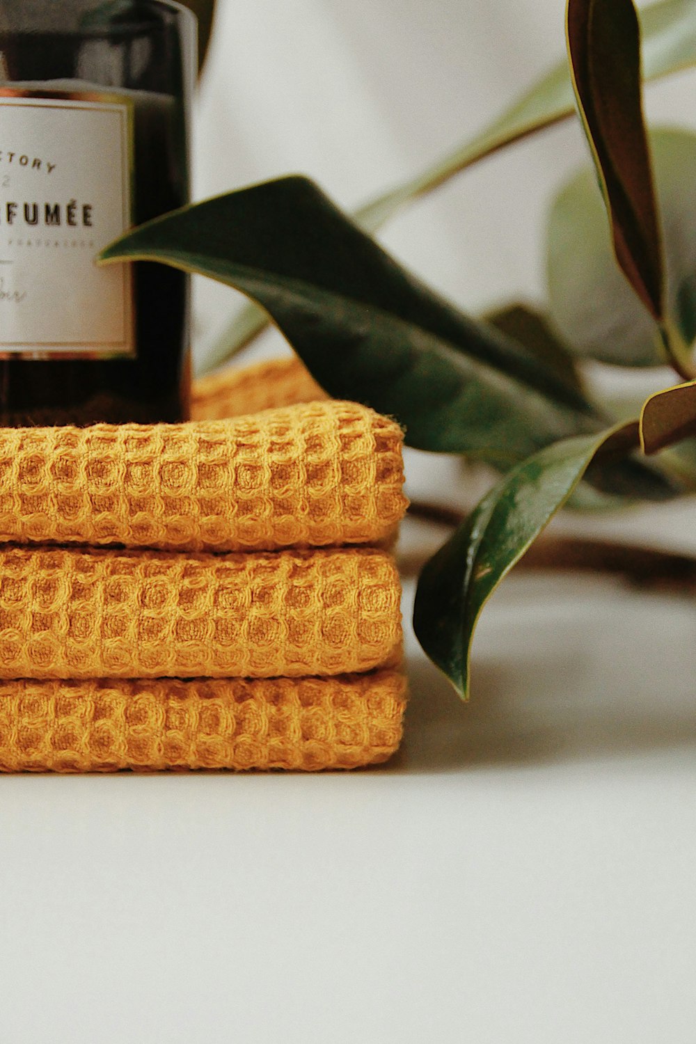 a stack of yellow towels next to a bottle of perfume