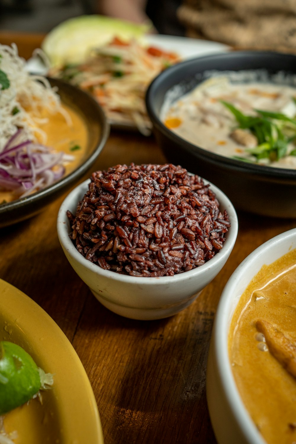 a wooden table topped with bowls of food