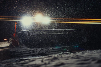 A snowplow clearing a driveway early in the morning with fresh snow falling.