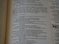 An open book with text on both visible pages, focusing on written content and paragraphs. The text includes religious or biblical references and verses can be identified.