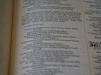 An open book with text on both visible pages, focusing on written content and paragraphs. The text includes religious or biblical references and verses can be identified.
