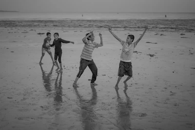 Children playing barefoot on sun-drenched sand, their joy captured candidly.