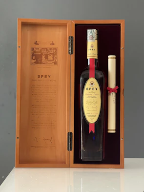 An elegant gift box open to reveal a whiskey smoker and ice stones nestled in soft amber-toned fabric.